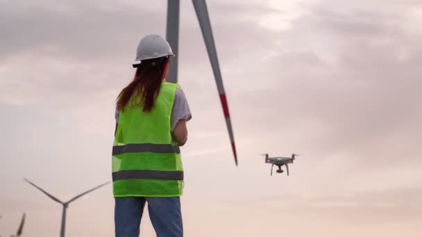 Frau mit Joystick steuert fliegende Drohne und überprüft korrekten Betrieb der Windmühle — Stockvideo