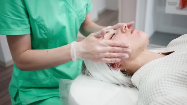 Femme esthéticienne rend rajeunissement du visage et procédure de nettoyage pour fille — Video