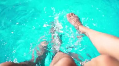 Sıcak Yaz Gününde Havuz kenarındaki Mavi Su 'nun arka planında Erkek ve Kadın Bacakları