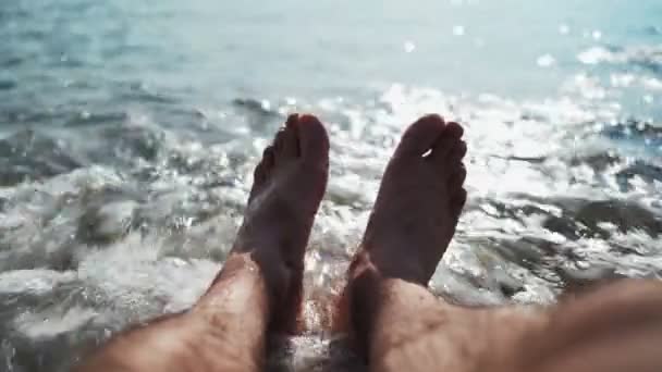 Piernas hombre irreconocible relajarse en la playa del mar en el día de verano. Vacaciones y viajes — Vídeos de Stock