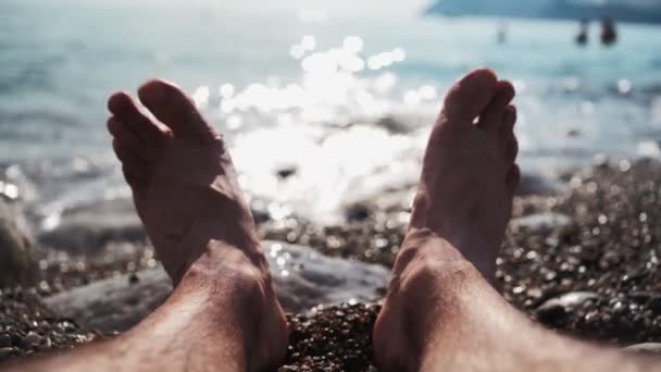 Piernas hombre irreconocible relajarse en la playa del mar en el día de verano. Vacaciones y viajes — Vídeos de Stock