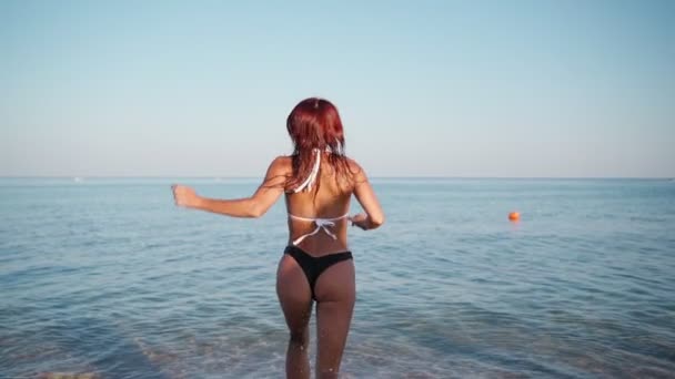 Young Happy Woman with Red Hair in a Swimsuit Runs into the Sea for a Swim. — стоковое видео