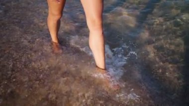 Deniz kıyısında yürüyen seksi kadın bacakları. Deniz suyunda yalınayak yürüyen kadın.
