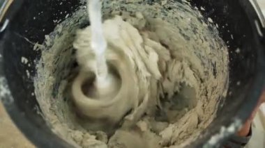 Kovada çimento harcı karıştıran işçilerin yakın çekimi. Daire yenileme konsepti