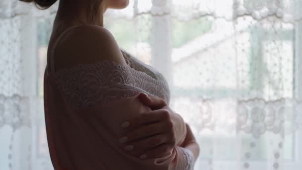 Ensam kvinna i morgonrock och underkläder står vid fönstret hemma. Ensamhet och sorg — Stockvideo