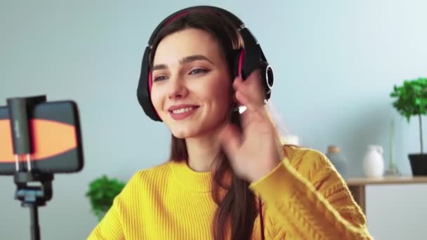 Happy young teacher in headphones communicates by video call using mobile phone. — Stock Video