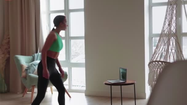 Passer ung slank kvinde gør fitness med online træner ved hjælp af bærbar computer hjemme. – Stock-video