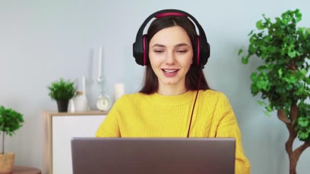 Ελκυστική γυναίκα στα ακουστικά επικοινωνεί με την επικοινωνία βίντεο χρησιμοποιώντας φορητό υπολογιστή — Αρχείο Βίντεο