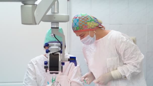 Dos cirujanas realizan cirugía ocular con microscopio e instrumentos médicos — Vídeos de Stock