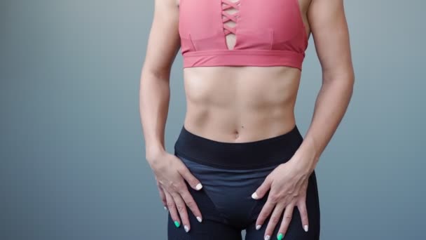 Atletická žena zkoumá své krásné svalnaté břicho. Štíhlé a štíhlé