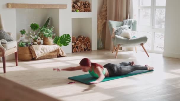 Atletisk kvinna gör fitness hemma gör nedre ryggmusklerna motion. — Stockvideo