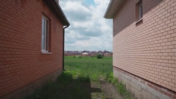 Neue einstöckige Backsteinhäuser vor dem Hintergrund von Feld und Privatwirtschaft — Stockvideo