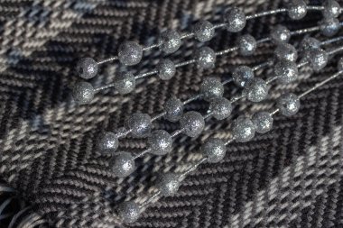 Siyah ve beyaz ringa balığı desenli, ışıltılı tatil takılarıyla süslenmiş yün atkı tam kare makro desen görünümü