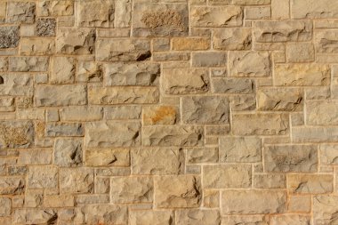 Değişen boyutlarda doğal bej renkli taş bloklar ve kül desenli dikdörtgen şekilli çekici bir kireç taşı bina duvarının tam çerçeve dokusu