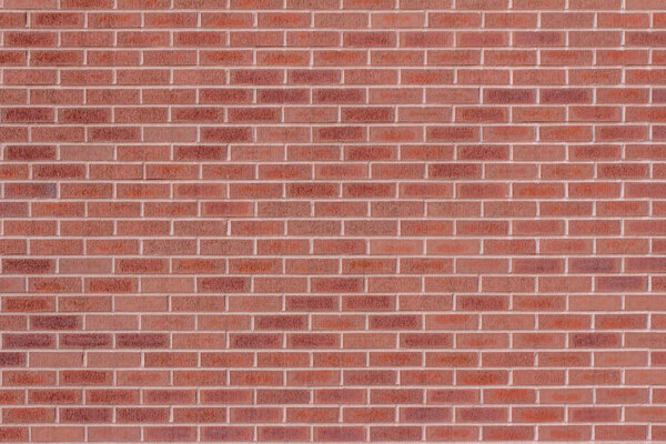 Full frame texture background of an attractive modern brick wall, with textured bricks in varying shades of red, in a traditional running bond brickwork pattern