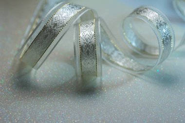 Işıldayan gümüş işlemeli kumaş şeritli, altın dikişli, beyaz parıltılı arka planda, kopyalama alanı olan tam kare makro desen arka plan.