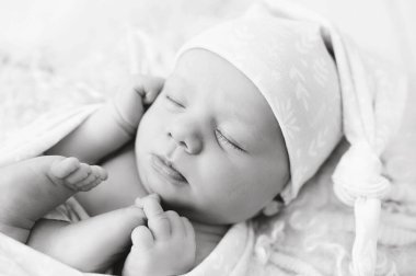 Yeni doğmuş bebek yün battaniyenin üzerinde uyuyor. Mutlu bebek, uyku zamanı. Siyah beyaz resim