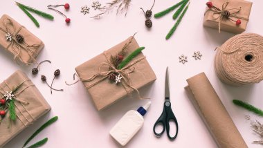 Çevre dostu ve sıfır atık Noel hediyesi paketine adım adım. Çevre ambalajı, makas, yapıştırıcı, kağıt, ip, düz uzanma materyalleri arasında doğal bitkilerle paketlenmiş ve dekore edilmiş