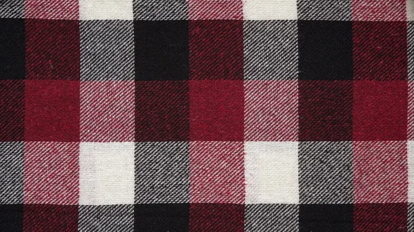 Texture of a woolen red-black-white plaid in a cage, close-up of fabric, textile winter background.Tartan fabric.Checkered pattern. — Stock Image Texture Woolen Red Black White Plaid Cage Close Fabric Textile Stock Photo