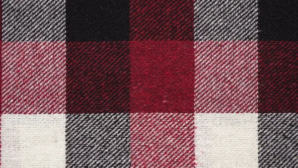 Texture of a woolen red-black-white plaid in a cage, close-up of fabric, textile winter background.Tartan fabric.Checkered pattern. — Stock Image Texture Woolen Red Black White Plaid Cage Close Fabric Textile Royalty Free Stock Photos