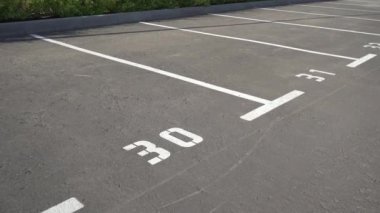 Otoparkta beyaz boya izi olan bir yere yakın plan. Boş otopark, beyaz işaretli otopark, halka açık park yeri. 30 numara. Video 4K.