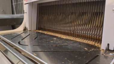 Elektrikli ekmek dilimleme makinesinin yakın çekimleri fırında, markette, süpermarkette ya da imalat tesisinde ince dilimlere bölünmüş ekmekler. Daha fazla ambalaj için ekmeklerin dilimlenmesi. Kadınların elleri ekmeği düzleştirir.