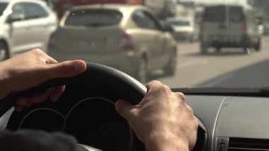  Güneşli bir günde trafik sıkışıklığında direksiyonda araba süren bir adamın yakın çekimi. Tatilde aile seyahati. Sürücüyle mal teslimatı. Seçici odaklanma, bulanık. 4K .