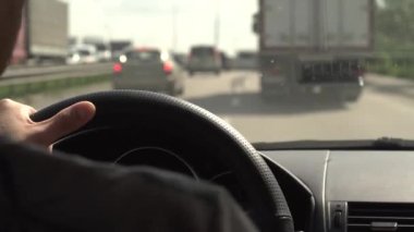  Güneşli bir günde trafik sıkışıklığında direksiyonda araba süren bir adamın yakın çekimi. Tatilde aile seyahati. Sürücüyle mal teslimatı. Seçici odaklanma, bulanık. 4K .