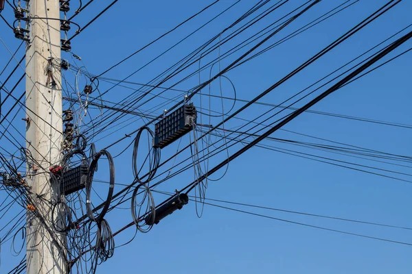 Elektrik direğindeki dağınık elektrik kabloları ve kablolar. Elektrik direklerinin etrafına bir sürü karışık elektrik kablosu, siyah beyaz elektrik direği.