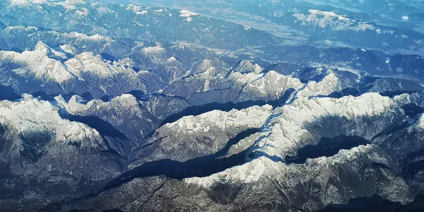 Karla kaplı tepeleri olan dağ sırasının havadan görünüşü