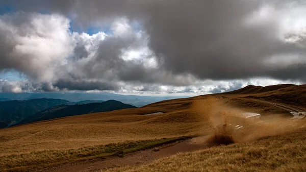 Offroad ekstrem araba arka planda güzel dağ manzarası ve dramatik gökyüzü ile çamurlu su sıçrıyor.
