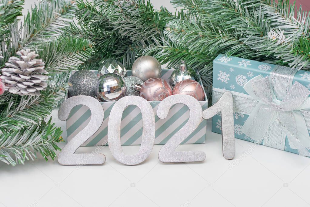silver numbers 2021 are standing against the background of fir branches with New Year's toys.concept - New Year's card, background for the presentation of work or text, New Year's mood.