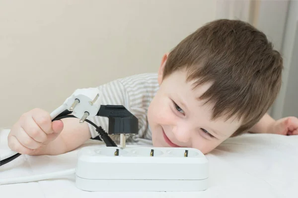 小男孩在玩电源插座和电线 孩子很高兴 他喜欢这样一个危险的游戏 横向照片 有选择的焦点 — 图库照片