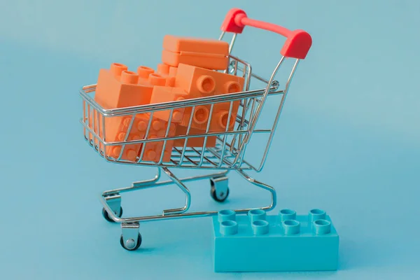 Close Mini Supermarket Cart Filled Orange Lego Bricks Blue Background — ストック写真