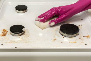 Kırmızı kauçuk eldivenli bir el köpüklü beyaz bir süngerle yıkanır, kirli bir mutfak gaz sobasıyla. Amaç evi temizlemek, dezenfekte etmek, temizlemek.