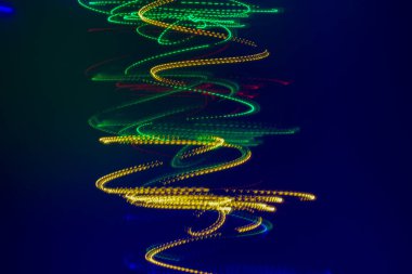 Koyu mavi arka planda, sarı ve yeşil ışıklardan oluşan bir spiral var. Yatay fotoğraf, soyut arkaplan.