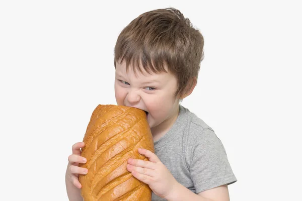 Chlapec Drží Rukou Velký Bochník Chleba Pokouší Něj Kousek Ukousnout — Stock fotografie