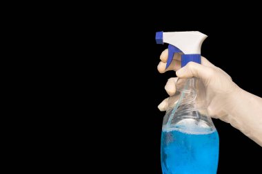 Plastik koruyucu eldivenli bir kadın siyah arka planda bir şişe temizlik malzemesi tutuyor. Yakın plan. Mutfak, banyo ve diğer alanlarda çeşitli yüzeyler için Deterjan. Boşluğu kopyala.