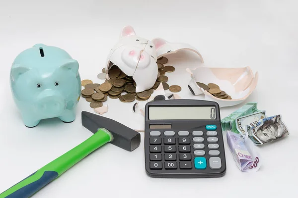 on a white background a piggy bank is broken with a hammer, there is a calculator and a whole piggy bank. Concept - lack of money, bankruptcy, calculations, counting money, investments.