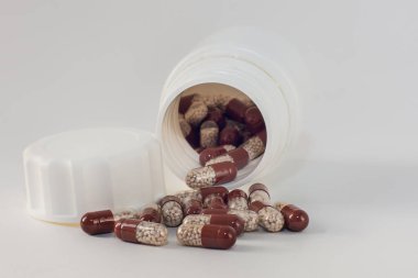 Beyaz granüllü kahverengi haplar. Beyaz arka plan, yakın plan. Haplar kavanozdan boşaldı. Yatay fotoğraf. İlaçlar, biyolojik olarak aktif katkı maddeleri, vitaminler. Paketi haplarla aç
