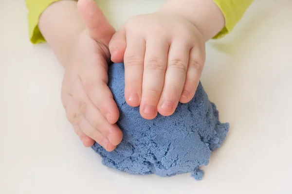 Kinderen handen close-up, beeldhouwen, spelen met blauw kinetisch zand. Het concept is gebaseerd op de ontwikkeling van fijne motorische vaardigheden, leervermogen, tastbare sensaties bij kinderen. Horizontale foto. — Stockfoto