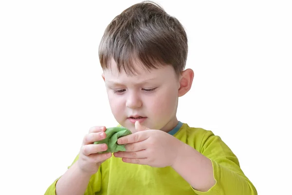 Jongen in groene kleren speelt met groene zachte plasticine. Het kind lacht niet, is geconcentreerd. Concept - educatieve spelletjes voor kinderen, ontwikkeling van creatief denken, fijne motoriek. — Stockfoto