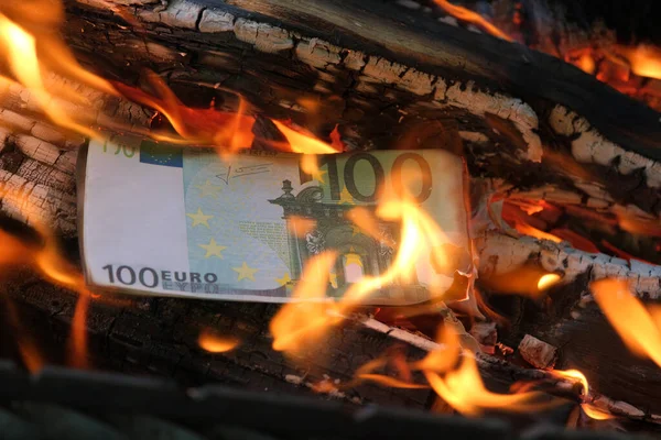 100欧元的钞票在熊熊烈火中燃烧。特写，横向照片。概念-危机、违约、经济衰退. 图库照片