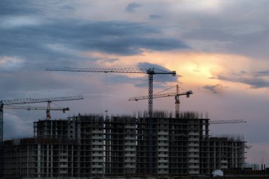 Güzel bir akşam gökyüzünün arka planına karşı inşaat alanı. İnşaat vinçleri. Vinç siluetleri. Yatay fotoğraf. İnşaat yapılıyor..