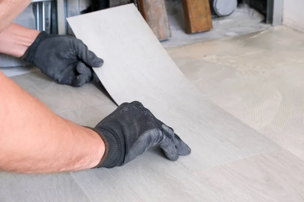 El primer plano de las manos de un hombre se encuentran en un laminado de cuarzo-vinilo. Reparación, trabajos de acabado. Suelos de unión. Foto horizontal. Suelos. Imágenes de stock libres de derechos