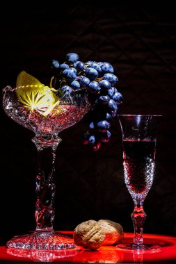 Üzümlü kristal bir vazo, bir dilim portakal ve kırmızı üzümlü şarap..