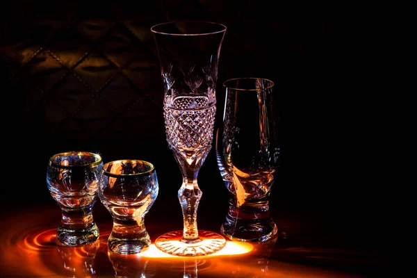 Aydınlatılmış bar tezgahında sert içkiler için şarap kadehleri ve bardaklar. Barın iç dekorasyonu.
