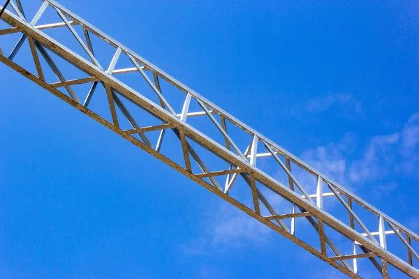 Steel truss made of metal corners against the blue sky. Structure of steel roof frame for building construction. Framework detail of metal bridge. Closeup bottom view