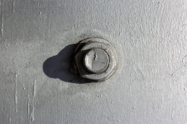 Large head bolt on metal construction as background - engineering concept. Metal head of bolt mounted on a metal surface. Hard shadow from the bolt heads. Close up of bolts holding plates.