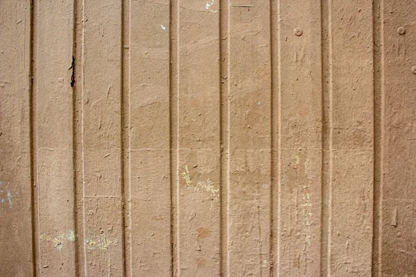 Corrugated sheet metal, badly painted with lightdo brown paint for background. Metal corrugated roofing sheet. Painting of metal surfaces for rust control. Abstract background for sites and layouts